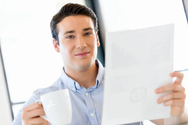 Jovem empresário no cargo com uma caneca — Fotografia de Stock