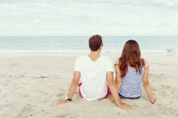 Romantische jonge paar zittend op het strand — Stockfoto