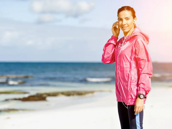 Femme sportive avec écouteurs sur la côte de la mer — Photo