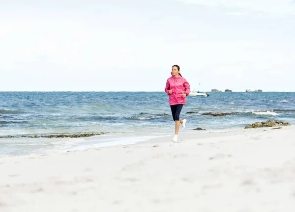 Jeune femme jogging sur la plage — Photo