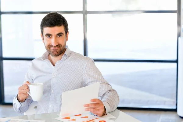 Guapo joven sosteniendo papel en la oficina — Foto de Stock