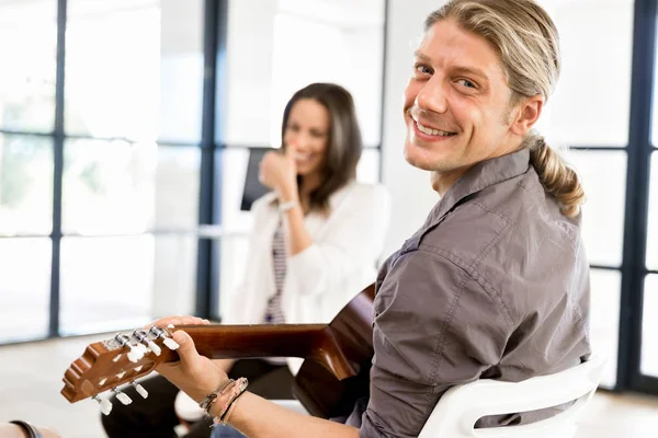 Jovem tocando guitarra no escritório — Fotografia de Stock