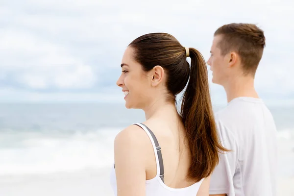 Jeune couple regardant réfléchi tout en se tenant à côté de l'autre sur la plage — Photo