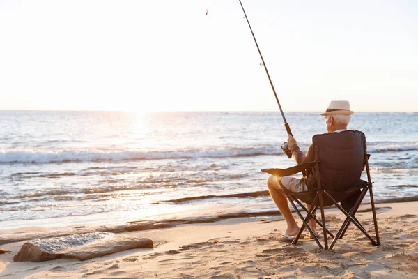 Senior man fishing at sea side — Stock Photo, Image