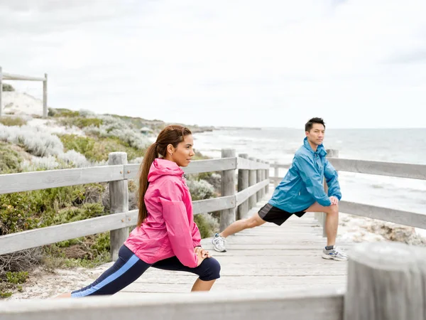 Jeune couple au bord de la mer faisant des exercices — Photo