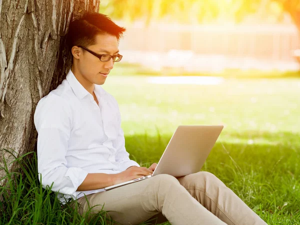 Jonge zakenman met behulp van laptop zittend buitenshuis — Stockfoto