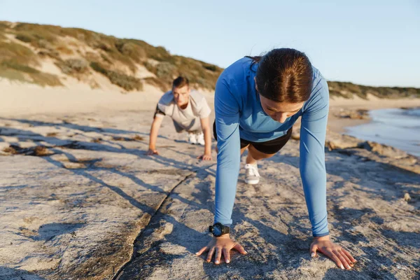 Mladý pár dělá push up na ocean beach — Stock fotografie