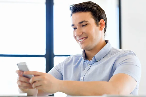 Självsäker ung man i smart fritidskläder som håller telefonen — Stockfoto