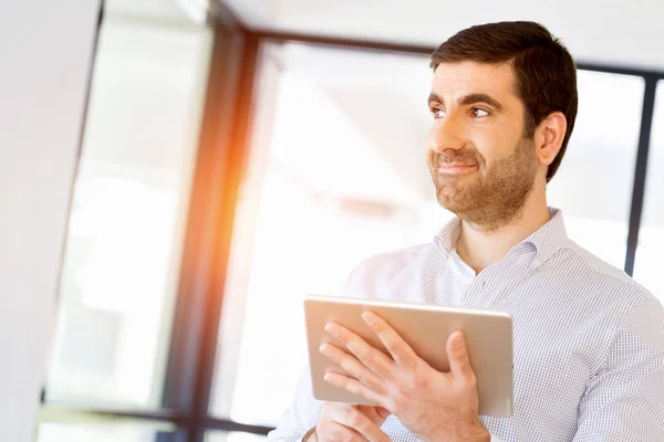 Jonge knappe zakenman zijn draagkracht touchpad gebruiken in office — Stockfoto