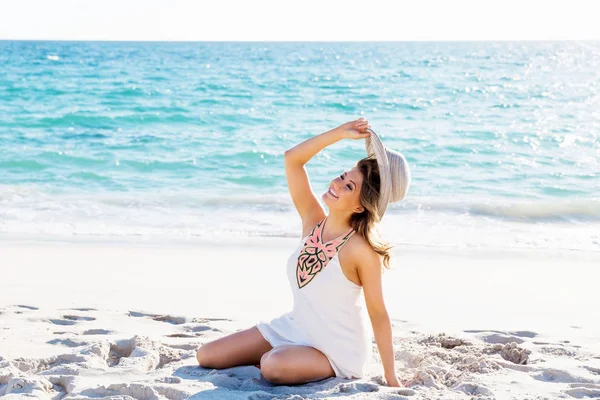 Jonge vrouw zittend op het strand — Stockfoto