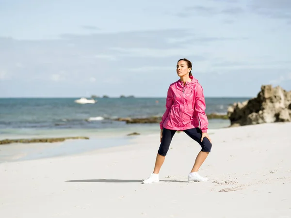 Ung kvinna på stranden gör övningar — Stockfoto