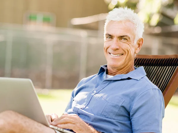 Senior man with notebook sitting in the park — Stock Photo, Image
