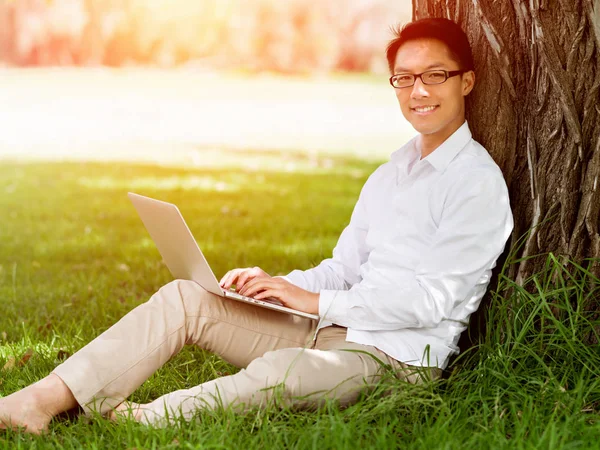 Genç işadamı açık havada otururken dizüstü bilgisayar kullanarak