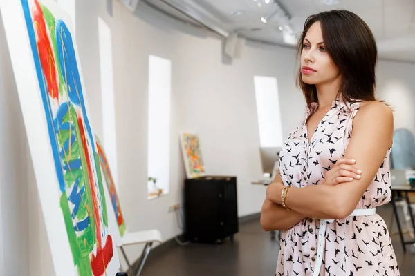 Young caucasian woman standing in art gallery front of  paintings — Stock Photo, Image
