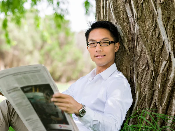 İş adamı parkta bir gazete okuyor