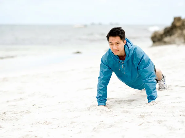 Jonge man doen oefening op het strand — Stockfoto