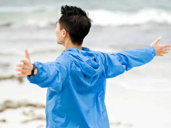 Giovane uomo con le braccia tese in spiaggia — Foto Stock