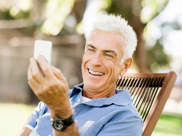 LoMature homme à l'extérieur en utilisant un téléphone mobile — Photo