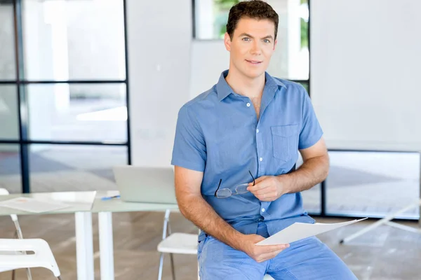 Young business man sitting on a stool in office — Stock Photo, Image