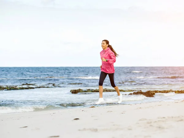 Jonge vrouw joggen op het strand — Stockfoto