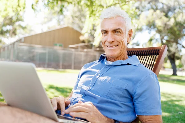 Senior férfi ül a parkban notebook — Stock Fotó