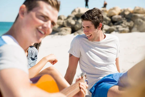 Schöne junge Leute mit Gitarre am Strand — Stockfoto