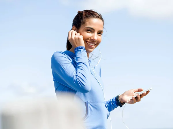 Sporty woman with earphones on the sea coast — Stock Photo, Image