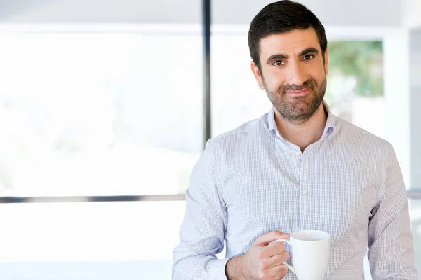 Jovem empresário no cargo com uma caneca — Fotografia de Stock