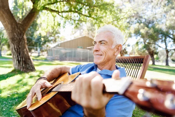Старший чоловік лежить на гітарі на відкритому повітрі — стокове фото