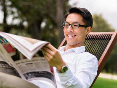 İş adamı parkta bir gazete okuyor