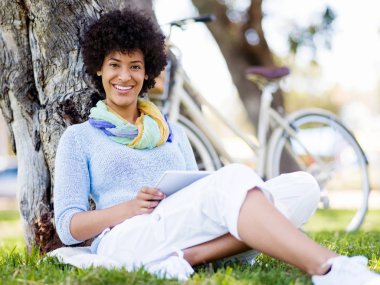 Parkta tablet kullanan genç bir kadın..