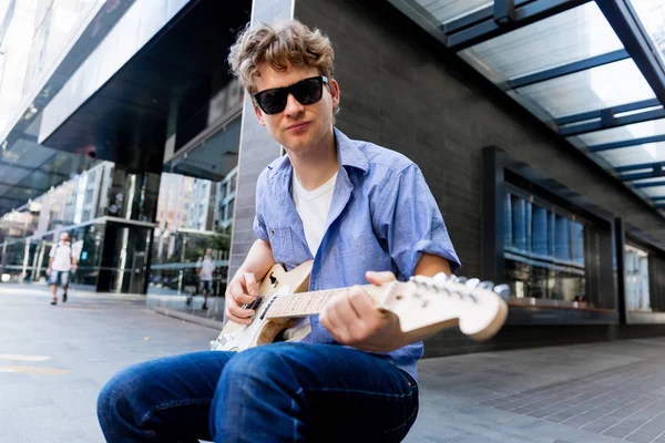 Joven músico con guitarra en la ciudad — Foto de Stock