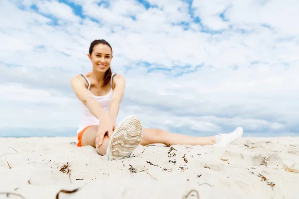 Mujer joven entrenando en la playa afuera — Foto de Stock