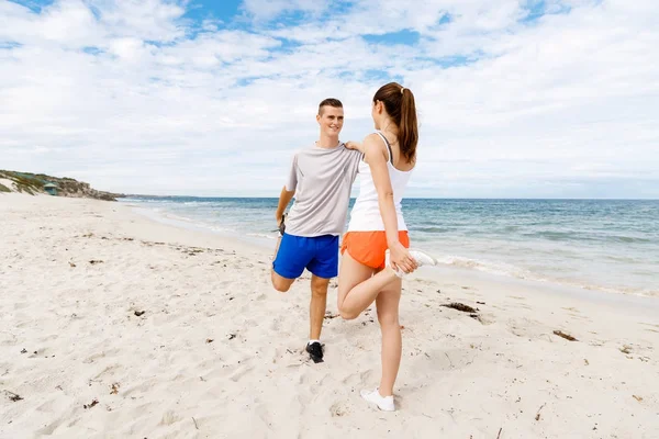 Kaçakçıları. Egzersiz ve stertching sahilde genç Çift