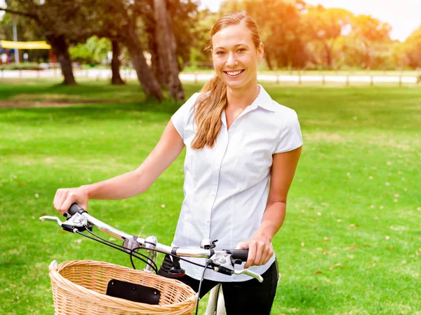Красивая молодая блондинка с велосипедом в парке — стоковое фото