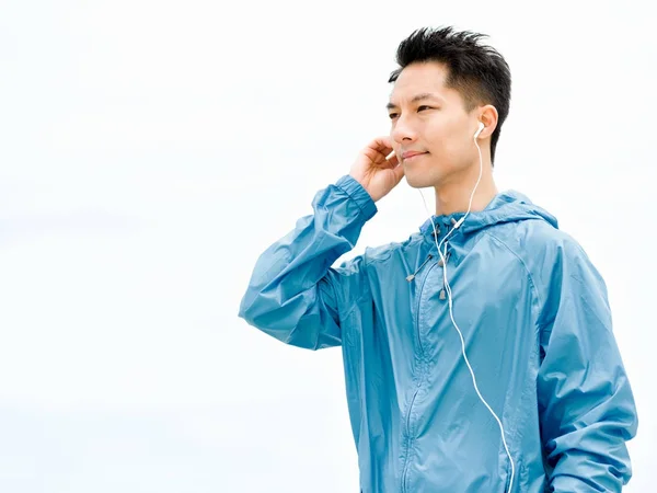 Sportieve man met koptelefoon aan de kust van de zee — Stockfoto