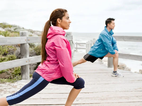 Young couple at the seaside doing exercises — Stock Photo, Image