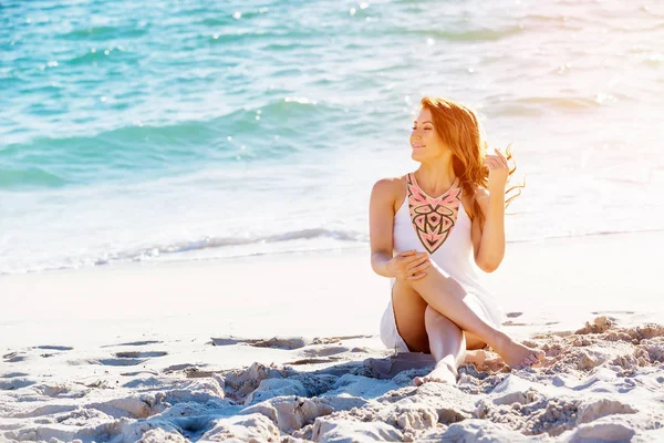 Junge Frau sitzt am Strand — Stockfoto