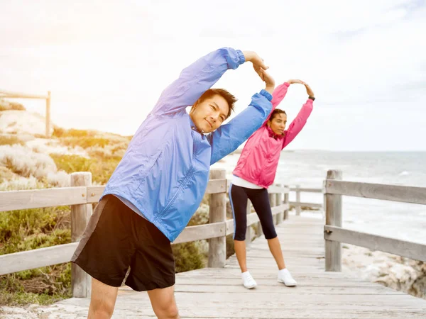 Jeune couple au bord de la mer faisant des exercices — Photo