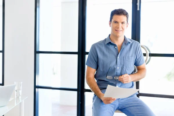 Young business man sitting on a stool in office — Stock Photo, Image