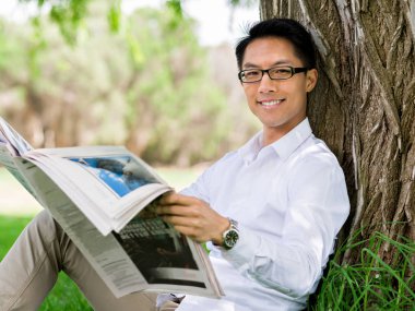 İş adamı parkta bir gazete okuyor