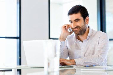 Kendine güvenen genç adam akıllı rahat kıyafet telefon tutarak