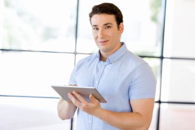 Genç yakışıklı işadamı onun touchpad ayakta kullanma office