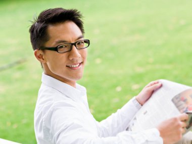 İş adamı parkta bir gazete okuyor