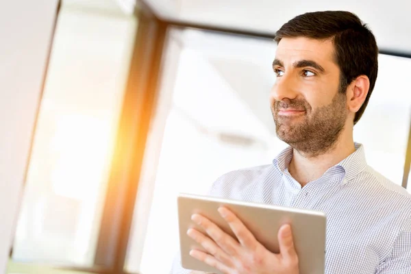 Ung snygg affärsman använder hans touchpad stående i office — Stockfoto