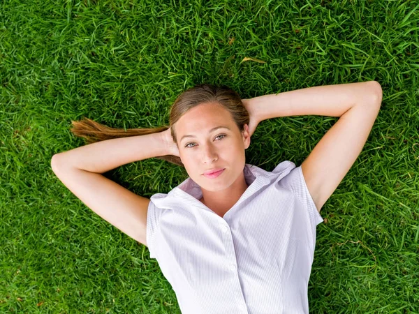 Jovem mulher bonita relaxante em uma grama — Fotografia de Stock