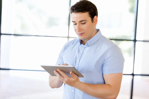 Ung snygg affärsman använder hans touchpad stående i office — Stockfoto