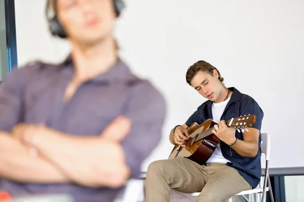 Young man playing the guitar in office — Stock Photo, Image