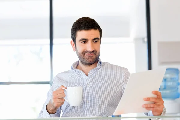 Handsome young man holding paper in office — Stock Photo, Image