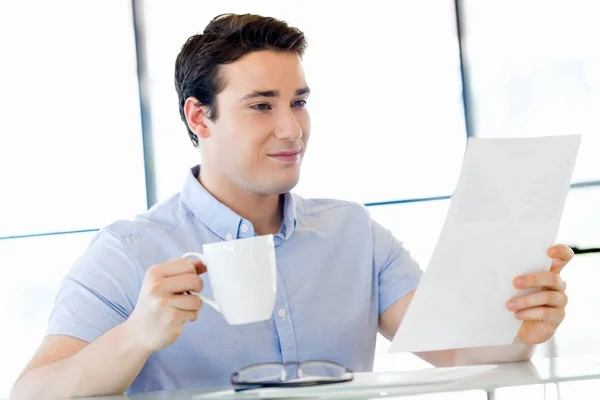 Молодий бізнесмен в офісі з чашкою — стокове фото